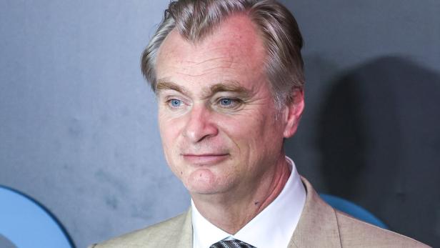 Der Regisseur Christopher Nolan blickt mit einem leichten Lächeln zur Seite.