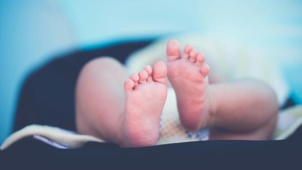 Nahaufnahme der nackten Füße eines Babys in einer Babyschale.
