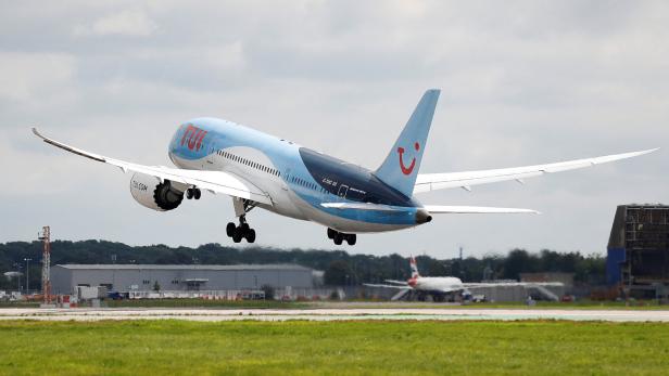 TUI-Flugzeug mit ausgefahrenem Fahrwerk kurz vor der Landung über einer Landebahn.