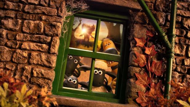 Shaun das Schaf und seine Freunde schauen neugierig aus einem Fenster eines alten Steinhauses auf eine sonnige Landschaft.