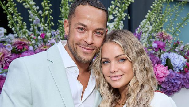 Andrej Mangold und Annika Jung posieren bei einem Termin und halten sichtbar den Babybauch.
