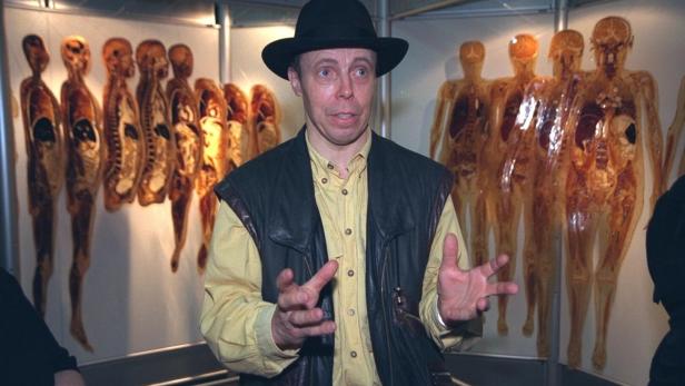 Gunther von Hagens steht vor Exponaten seiner Ausstellung „Körperwelten“ und erklärt mit gestikulierenden Händen die anatomischen Schnitte.