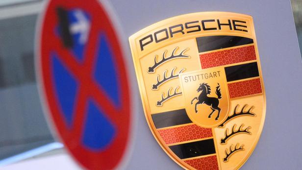Das Porsche-Wappen ist scharf abgebildet, während im unscharfen Vordergrund ein absolutes Halteverbotsschild zu sehen ist.