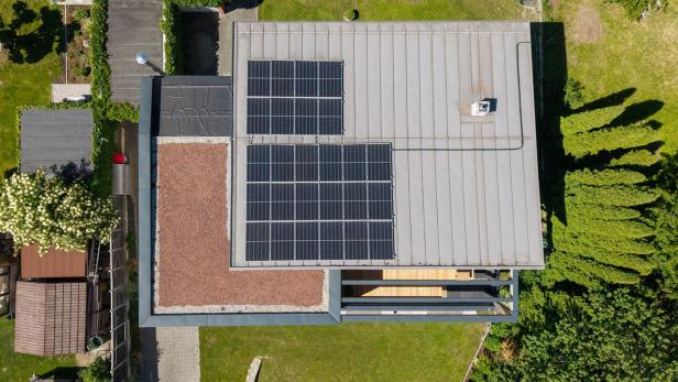 Luftaufnahme eines modernisierten Hausdachs mit Solarmodulen.