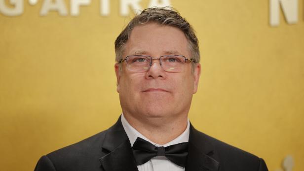 Sean Astin trägt einen schwarzen Smoking mit Fliege vor einem gelben Hintergrund mit dem SAG-AFTRA-Logo.