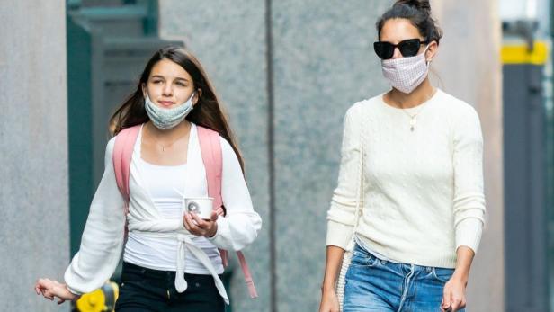 Suri Cruise geht mit Katie Holmes maskiert durch eine Straße in New York.