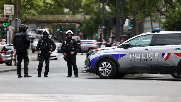 Polizisten sichern eine abgesperrte Straße neben einem Polizeiwagen.