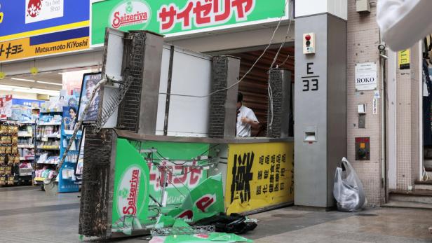 Zerstörte Saizeriya-Werbetafel in einer japanischen Einkaufsstraße.