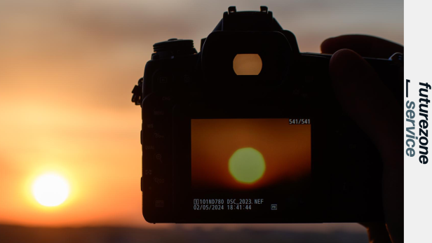 Eine Kamera fotografiert die tief stehende Sonne im Sonnenuntergang.