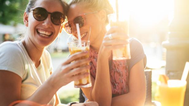 Zwei Frauen trinken gemeinsam einen Cocktail.