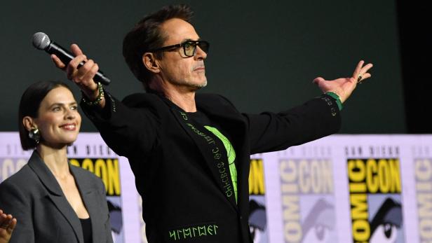 Robert Downey Jr. steht mit ausgebreiteten Armen und einem Mikrofon auf der Bühne der San Diego Comic-Con neben Hayley Atwell.
