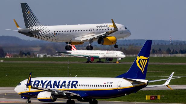 Zwei Ryanair-Flugzeuge am Flughafen, eines rollt am Boden, eines landet darüber.