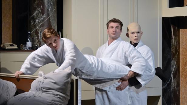 Drei Schauspieler in Bademänteln während einer Theatervorstellung.