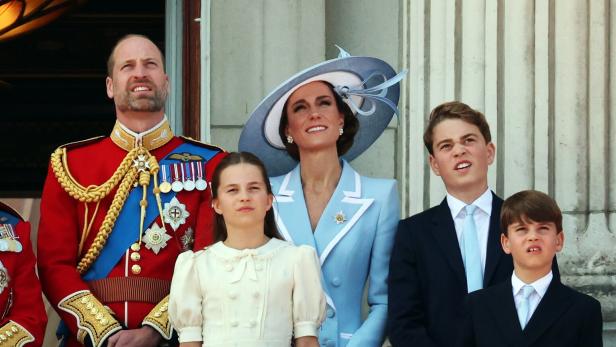Prinz William, Prinzessin Kate und ihre Kinder George, Charlotte und Louis stehen auf einem Balkon und blicken gemeinsam nach oben.