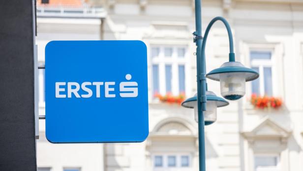Blaues ERSTE-Schild an einer Gebäudefassade neben einer Straßenlampe.