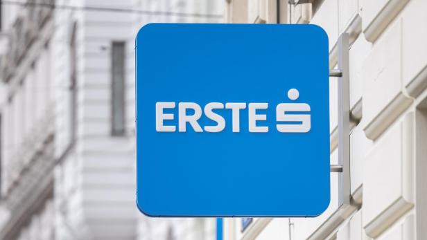 Straßenschild von Erste an einer Häuserfassade, darunter mehrere Verkehrszeichen.