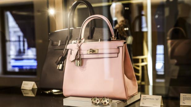 Rosa Handtasche mit Schloss in einer Luxusvitrine, daneben passende Ohrringe.