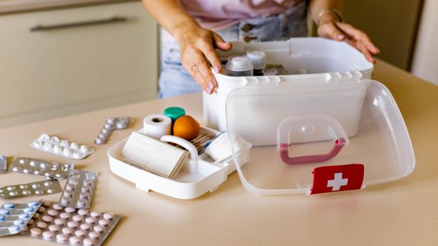 Closeup female hand placing medicament domestic first aid kit. Storage organization emergency supply