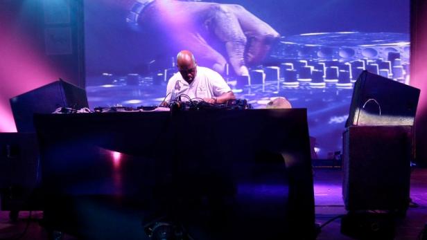 Ein DJ legt auf einer Bühne mit großer Leinwand auf.