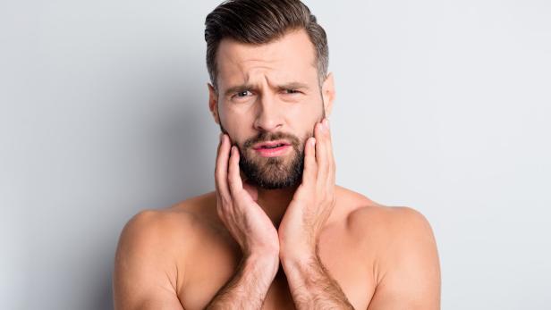 Photo of young handsome man unhappy sad upset displeased problem hand touch beard isolated over grey color background