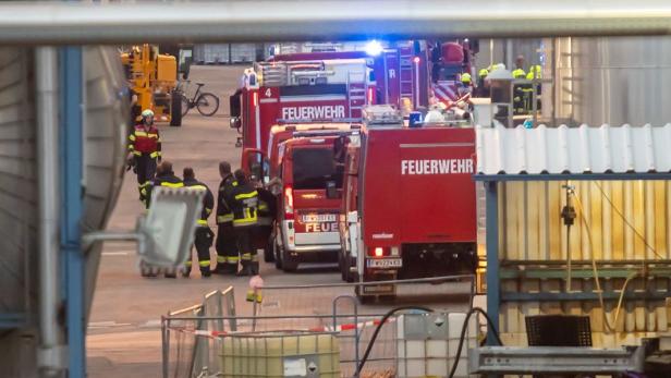 Feuerwehrleute und Einsatzfahrzeuge in einem Industriegelände.