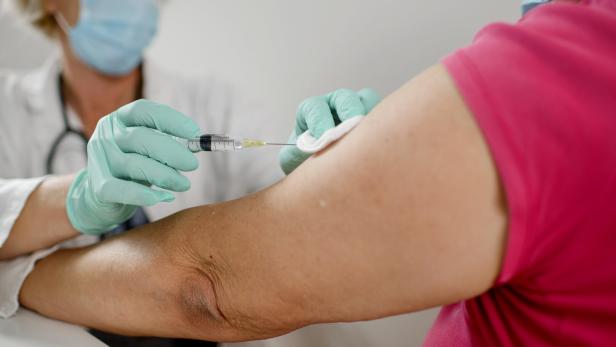 Female doctor makes vaccination to woman. They are wearing a protective face masks.