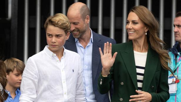 Prinz William, Prinzessin Kate und Prinz George bei einem öffentlichen Auftritt, bei dem Kate freundlich in die Menge winkt.