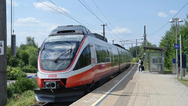 ÖBB-Zug an einem Bahnsteig, daneben wartet eine Person mit Gepäck.