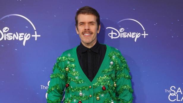 Perez Hilton in grünem, festlich geschmücktem Weihnachtspullover vor Disney+-Hintergrund.