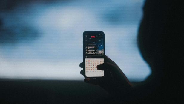 Eine Hand hält ein Smartphone mit laufendem Livestream.
