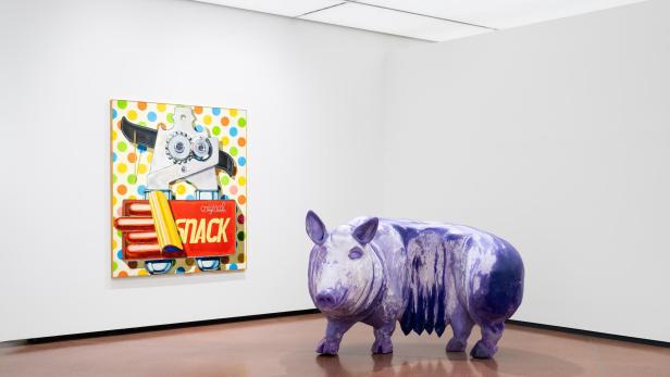 Violettes Schwein vor farbigem „Snack“-Gemälde in einem Ausstellungsraum.
