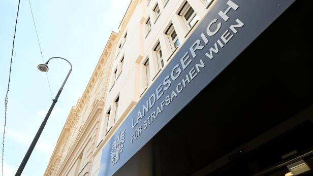 Schräger Blick auf ein Wiener Landesgericht mit Straßenschild und Straßenlaterne.