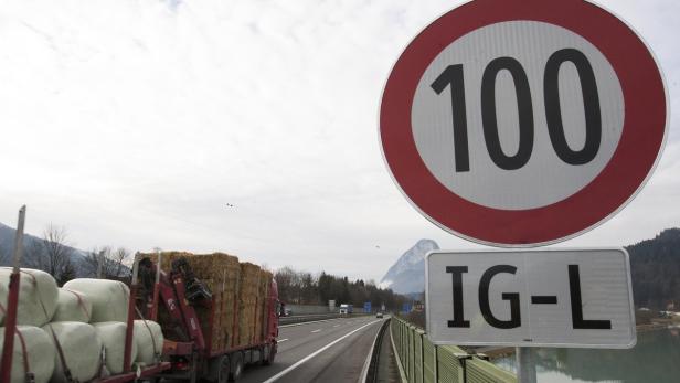Ein Lastwagen mit Heuballen fährt auf einer Autobahn unter einem Tempolimit-Schild (100 km/h) und einem IG-L Schild.