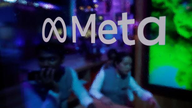 FILE PHOTO: People are seen behind a logo of Meta Platforms, during a conference in Mumbai