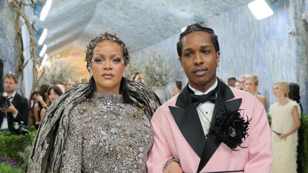 Rihanna in einem silbernen, strukturierten Kleid und Asap Rocky in einem rosa Mantel posieren gemeinsam auf dem roten Teppich.