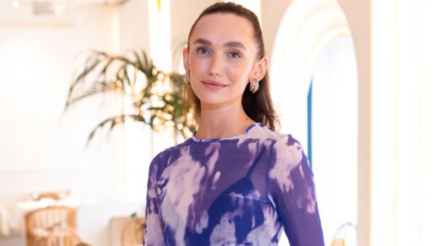 Anna Adamyan posiert in einem hellen Restaurant mit lila Oberteil und Jeans.