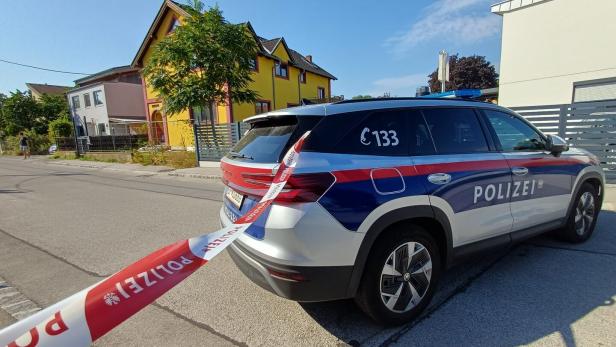 Polizeiwagen in Absperrband vor Wohnhäusern auf einer Straße.