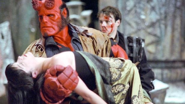 Hellboy trägt eine bewusstlose Frau in seinen Armen.