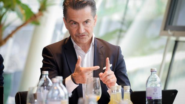Ein Mann im Anzug spricht bei einem Tischgespräch und gestikuliert mit den Händen.