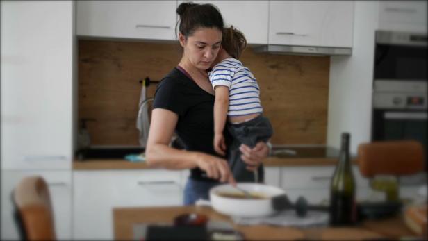Mother holding son while cooking mom multi-tasking at home preparing food
