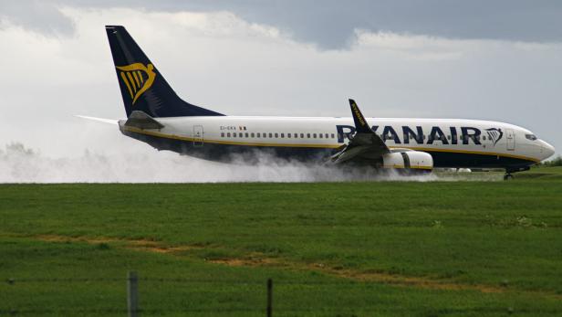Ryanair-Passagierflugzeug landet auf nasser Runway und wirbelt Wasser auf.