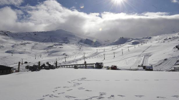 Eine verschneite Berglandschaft mit Skipisten und Liftanlagen unter einem bewölkten Himmel.