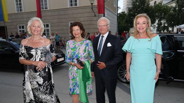 Königin Silvia und König Carl XVI. Gustaf von Schweden posieren gemeinsam mit zwei elegant gekleideten Frauen vor einem Gebäude.