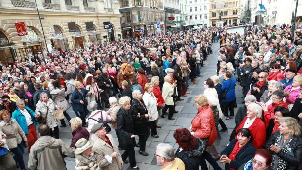 Eine große Menschenmenge tanzt auf einem Platz in der Stadt.