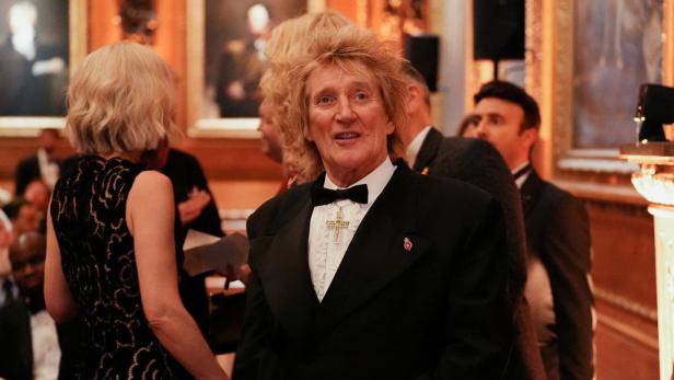 Rod Stewart trägt einen schwarzen Smoking mit Fliege und ein auffälliges Kreuz-Amulett bei einer formellen Veranstaltung.