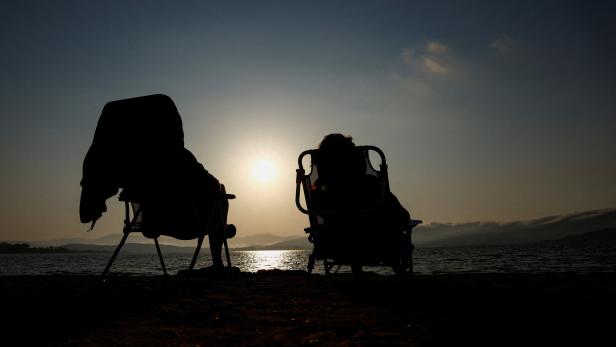 Patricia Molera and Enrique Sotomayor test their eclipse glasses during sunset at Arija beach