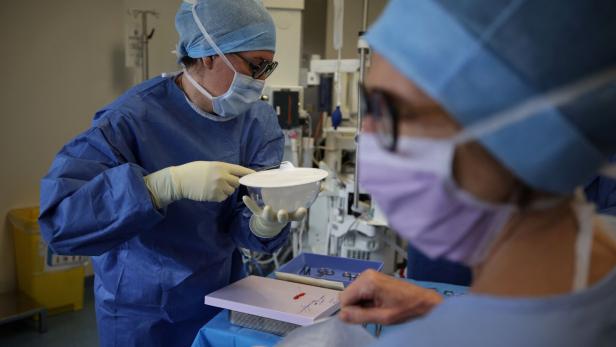 Zwei medizinische Fachkräfte in OP-Kleidung bereiten in einem Krankenhaus sterile Instrumente und Materialien für einen Eingriff vor.
