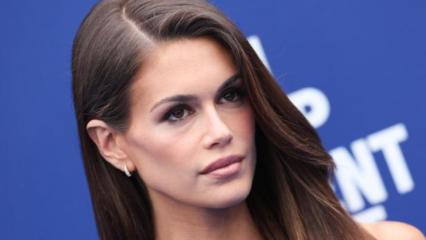 Nahaufnahme von Kaia Gerber vor einem blauen Hintergrund.