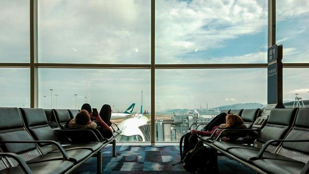 Zwei Personen liegen auf Sitzbänken am Flughafen