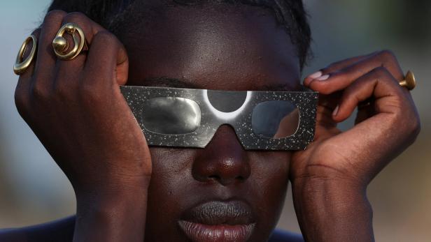 A woman observes a partial solar eclipse in Dakar